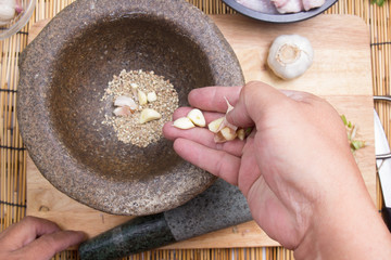 Chef putting garlic to mortar