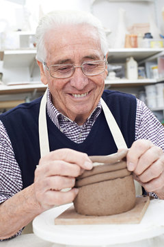 Senior Man Making Coil Pot In Pottery Studio