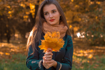 Naklejka na ściany i meble young girl looks thoughtful and holds the dry leaves