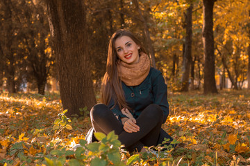 young girl is sitting on the ground in autumn Park