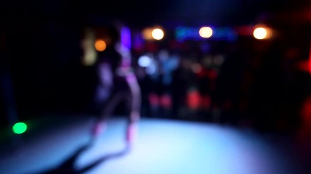 Girl dancing on stage on blurred background in the night club