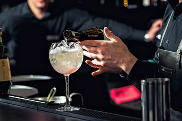 Closeup of bartender hands pouring alcoholic drink into a jigger