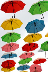 Colorful, hanging umbrellas on white .
