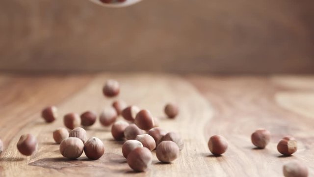 Slow motion of unpeeleed hazelnuts falling on wood table, 180fps prores footage