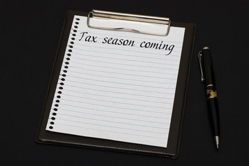 Top view of clipboard and white sheet written with Tax season co