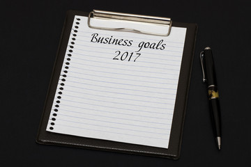 Top view of clipboard and white sheet written with Business goal