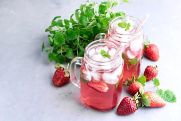 Strawberry lemonade with ice and mint in glass mug jars
