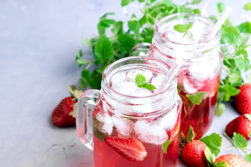 Strawberry lemonade with ice and mint in glass mug jars