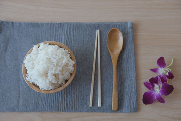 Cooked rice in a wooden bowl and spoon ,chopsticks on a wood background.