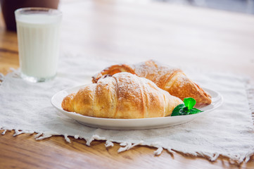Close up continental breakfast with assortment of fresh pastries and glass of milk on the background. Selective focus
