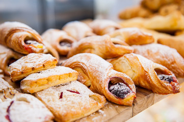 Close up freshly baked pastry goods on display in bakery shop. Selective focus