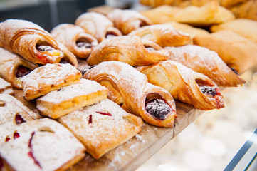 Close up freshly baked pastry goods on display in bakery shop. Selective focus - obrazy, fototapety, plakaty
