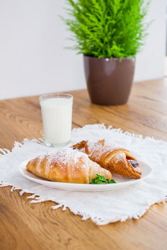 Served breakfast with assortment of fresh pastries and glass of milk on the wooden table. Selective focus