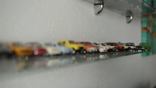 collection of toy cars on the glass shelf. camera focus moves on cars
