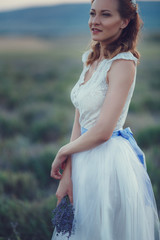 Fototapeta na wymiar Portrait of beautiful romantic woman in fairy field of lavender with bouquet