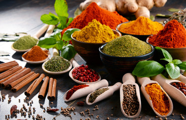 Variety of spices and herbs on kitchen table - obrazy, fototapety, plakaty