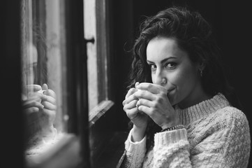 B&W  portrait of beautiful woman who drinks coffee close to the