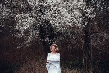 Young beautiful blonde woman in blooming garden. Bride.