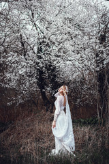 Young beautiful blonde woman in blooming garden. Bride.