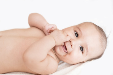 Smiling newborn baby lying on bed