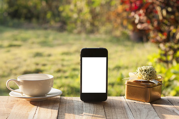 White blank screen(clipping path) smartphone for add content. on wood table in garden.