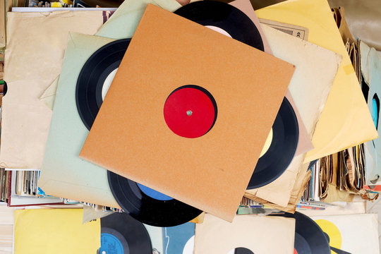 Retro styled image of a collection of old vinyl record lp's with sleeves on a wooden background. Top view. Copy space