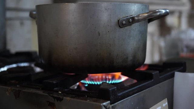 An old dirty cooker with a gas on and a old pan on it, selective focus, 4K