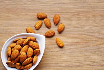 Bowl of almonds organic on a rustic wooden background. Picture design for eating healthy and weight loss concept.