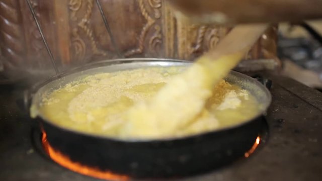Mixing corn flour in a cast iron pot to make polenta
