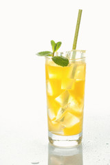 Glass of cold refreshing orange drink with ice and mint