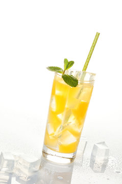 Glass of cold refreshing orange drink with ice and mint