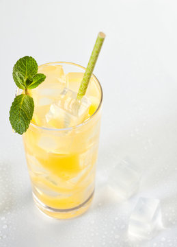 Glass of cold refreshing orange drink with ice and mint