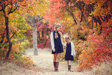Two cheerful sisters playing in the park in warm autumn day