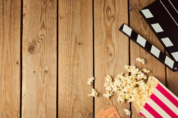 Movie clapper board and popcorn on wooden background. Top view from above