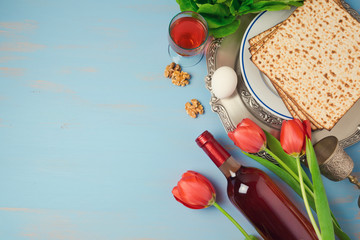 Obraz premium Passover holiday concept seder plate, matzoh and tulip flowers on wooden background. Top view from above