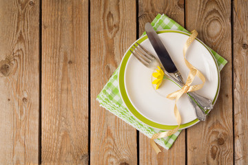 Easter holiday table setting with plate on wooden background. Top view from above