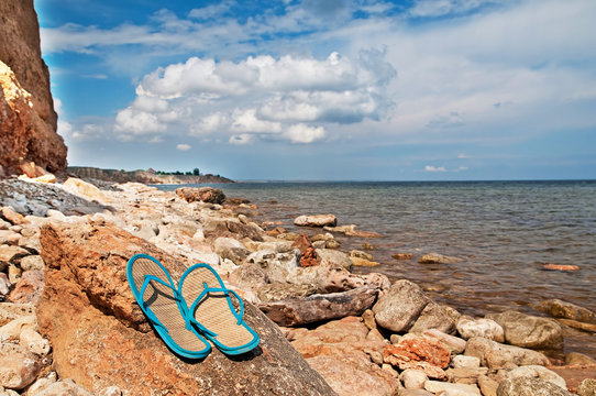 Pair of flip-flops on the stones near the sea
