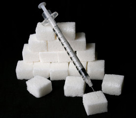 sugar adiction  syringe and sugar cubes over black background