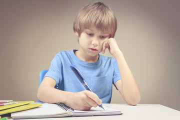 Boy writing on paper notebook. Boy doing his homework exercises