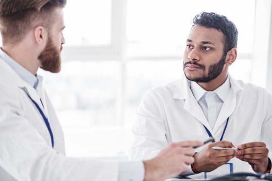 Calm physician listening his associate during colloquy