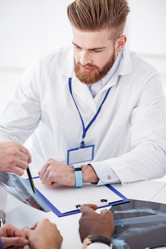 Calm physician watching at x-ray in clinic