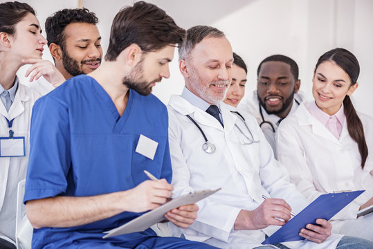Cheerful doctors watching at tablet of colleague