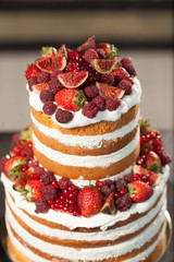 Naked cake on the black background. Cake with fresh berries and white cream.
