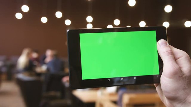 A man holds a blank tablet PC with a green screen for your own custom content.