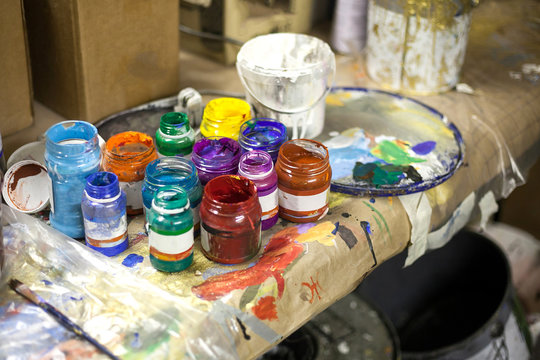 Multi colored paints in jars for drawing. Color paints for creativity on a white background. Boxes with paints on a table.