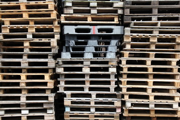 Stacked wooden and plastic pallets in an outdoor storage