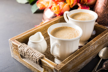 Mother and Valentines day, wedding concept with two cups of coffee in vintage wooden tray with orange roses. Copy space. Retro style toned.