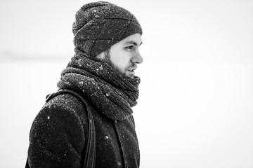 Outdoor portrait of handsome man in gray coat. Fashion photo. Beauty winter snowfall style. Black and White