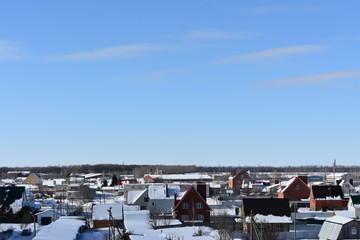 Fototapeta na wymiar winter city on the background of blue sky; building house covered with snow to the horizon; small clouds
