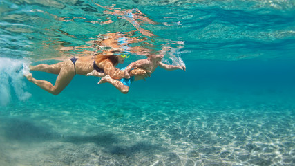 Happy family - mother with baby son dive underwater with fun in sea pool. Healthy lifestyle, active parent, people water sport outdoor adventure, swimming lessons on beach summer holidays with child